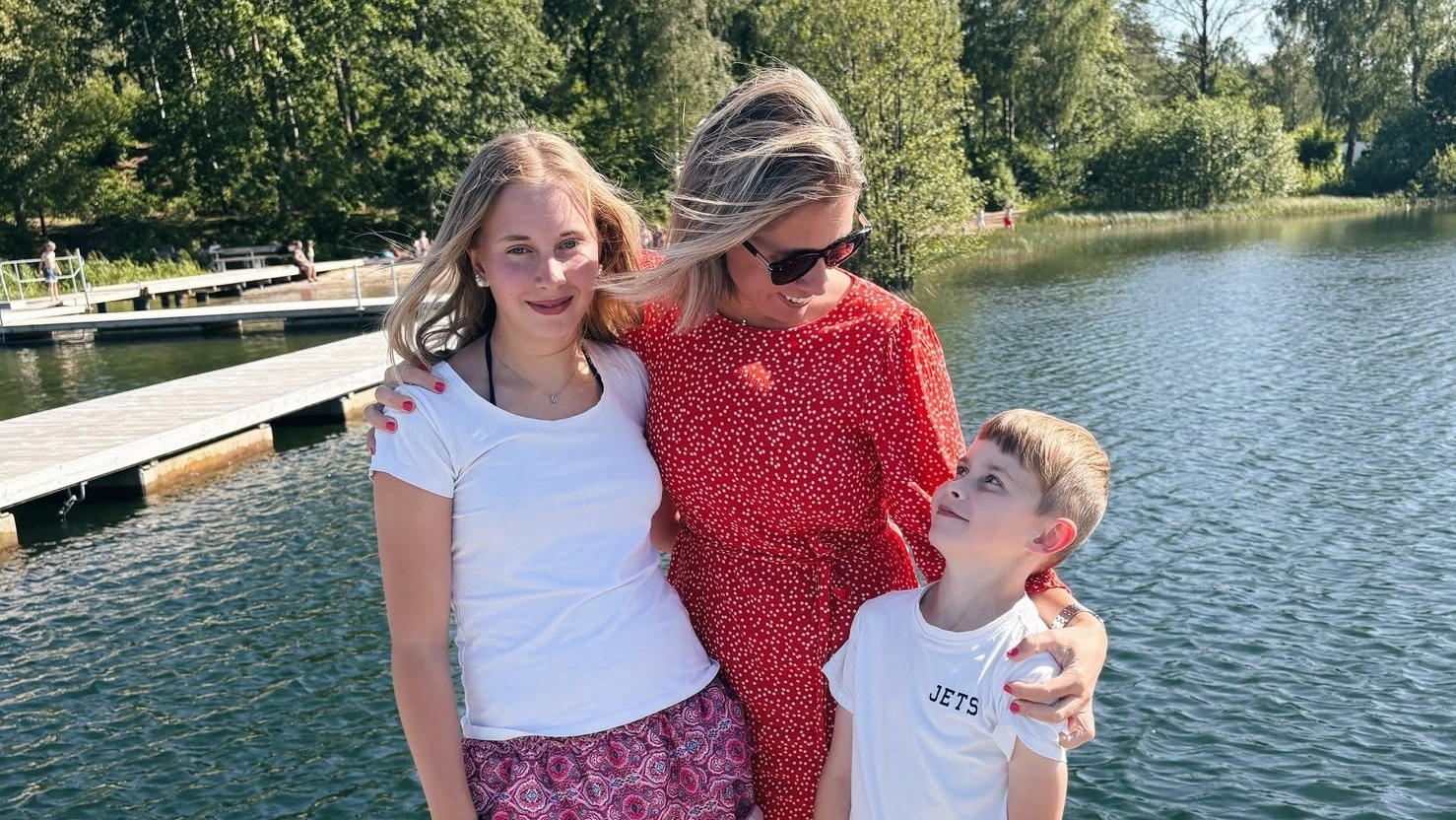 Ett foto på en mamma och hennes två barn i skogen framför en sjö