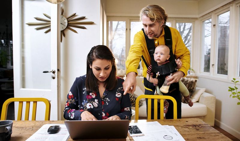 A couple with baby looking at laptop